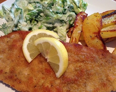 Panierte Schweineschnitzel dazu Kartoffelecken und Gurkensalat